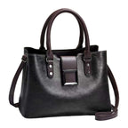 Black handbag with brown accents on a light surface with a beige background