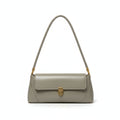 Green handbag hanging on a door handle against a white wall.