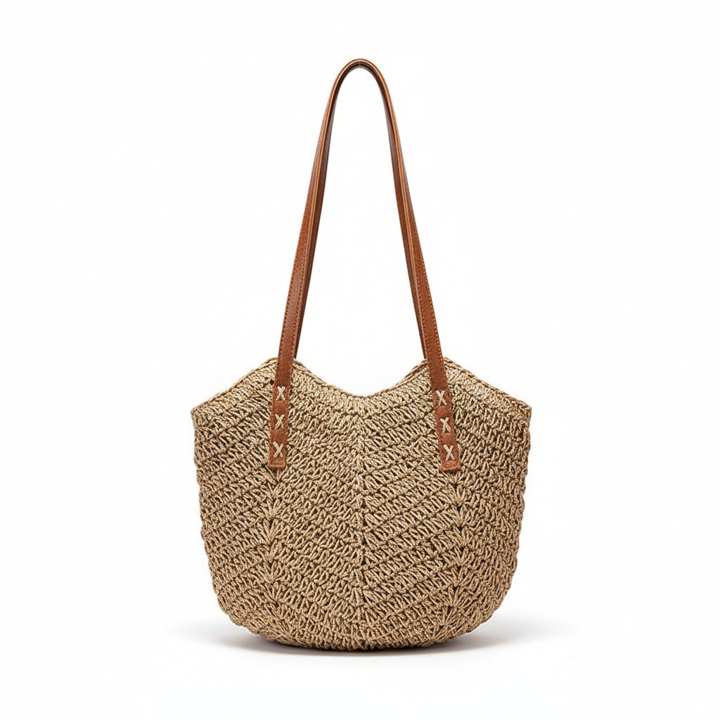 Woven handbag with brown handle on a surface next to a framed picture
