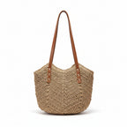 Woven handbag with brown handle on a surface next to a framed picture