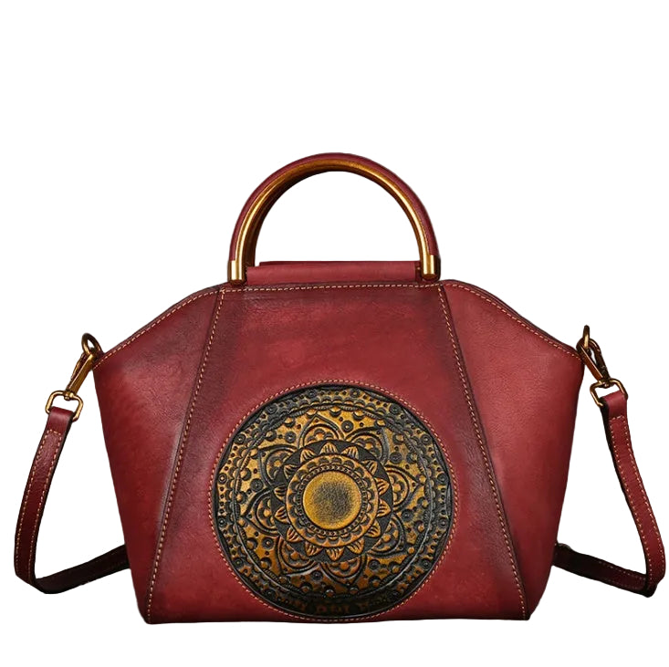 Red handbag with gold handle and decorative emblem on a textured gray background