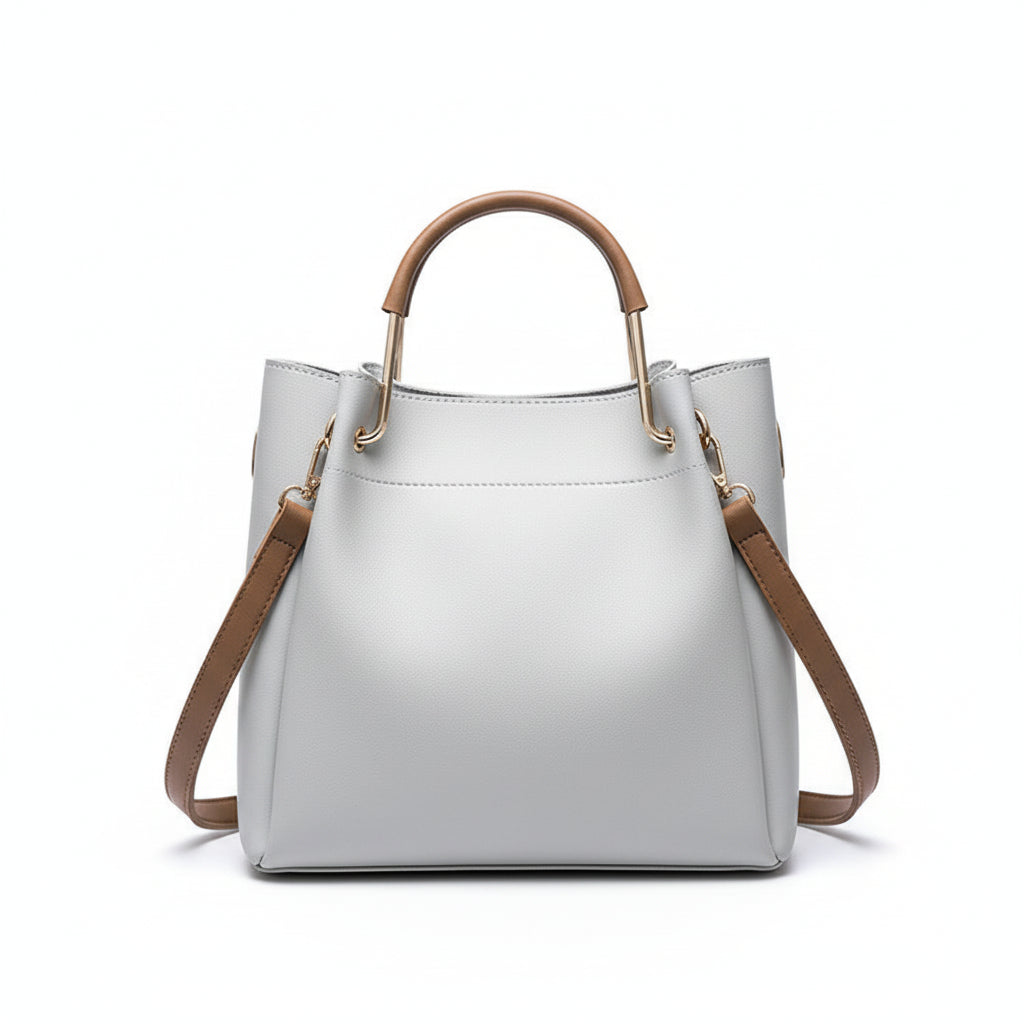 Gray handbag with brown handles and strap on a wooden surface