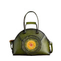 Green leather handbag with floral design on a brown textured background