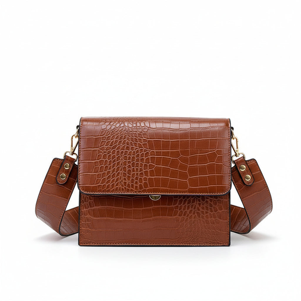 Brown crocodile-patterned handbag held by a person on a light background