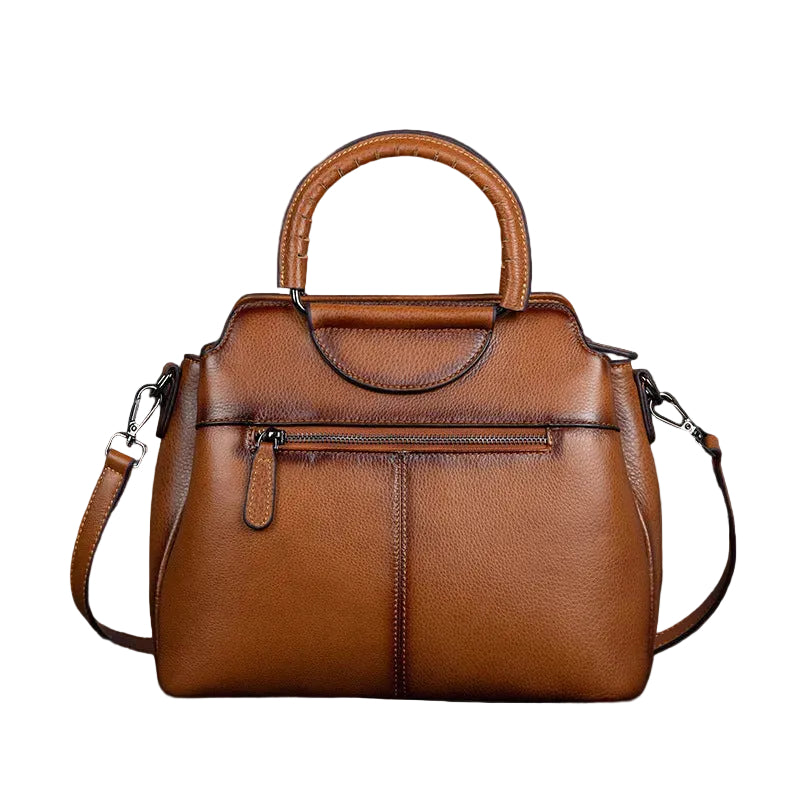 Brown leather handbag on a dark surface with a rustic background