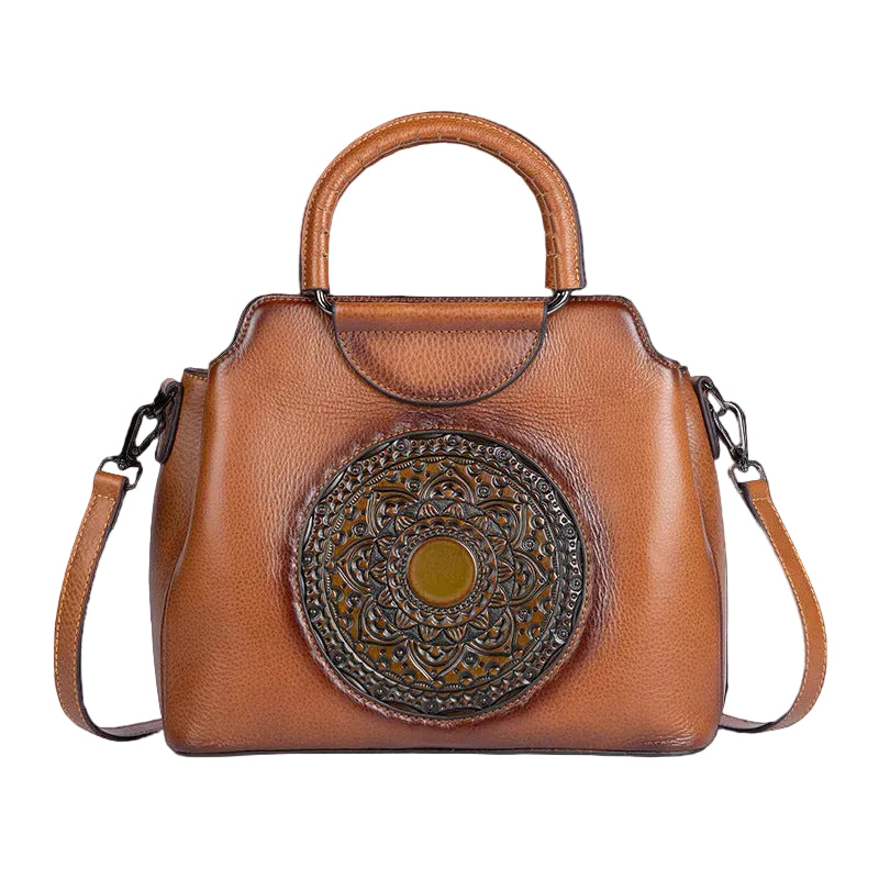 Brown leather handbag with decorative circular emblem on a white background