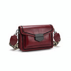Red handbag with a patterned strap on a beige blanket