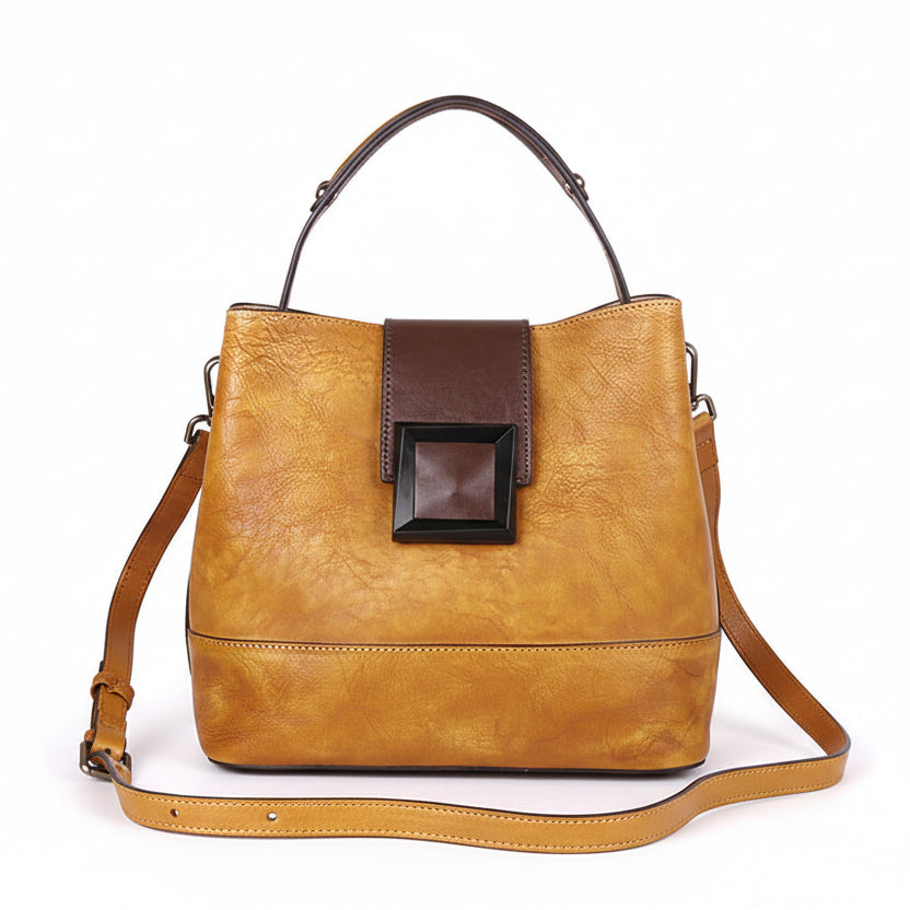 Brown leather handbag with a dark brown patch on a wooden surface.
