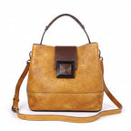 Brown leather handbag with a dark brown patch on a wooden surface.