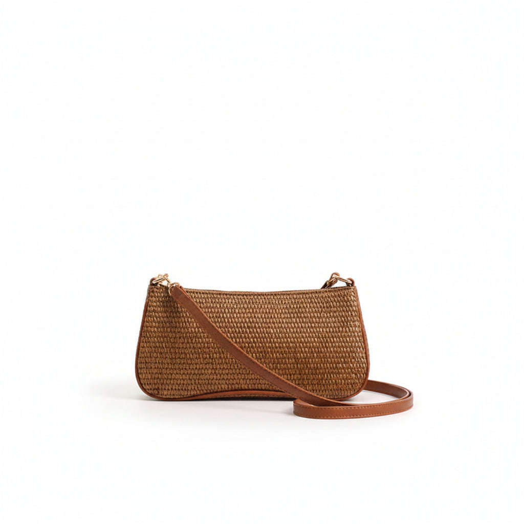 Person holding a brown straw handbag with a plain background