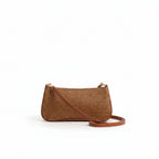 Person holding a brown straw handbag with a plain background