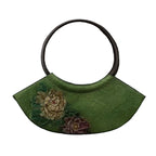 Green handbag with floral embroidery on a textured brown background