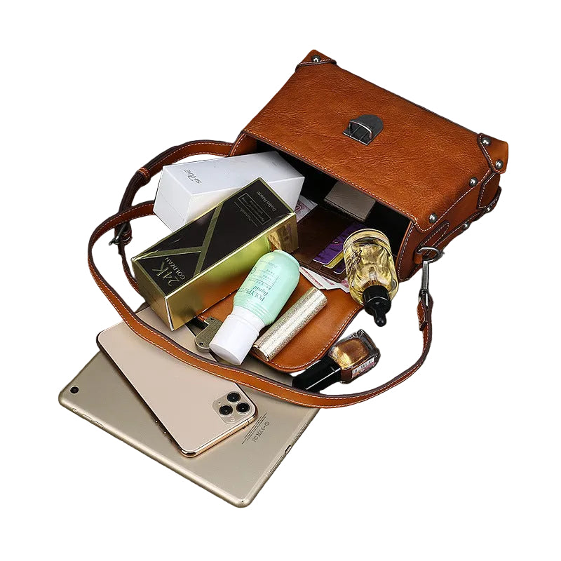 Open brown leather handbag with various items on a dark textured surface