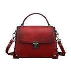 Red leather handbag with a silver clasp on a gray background