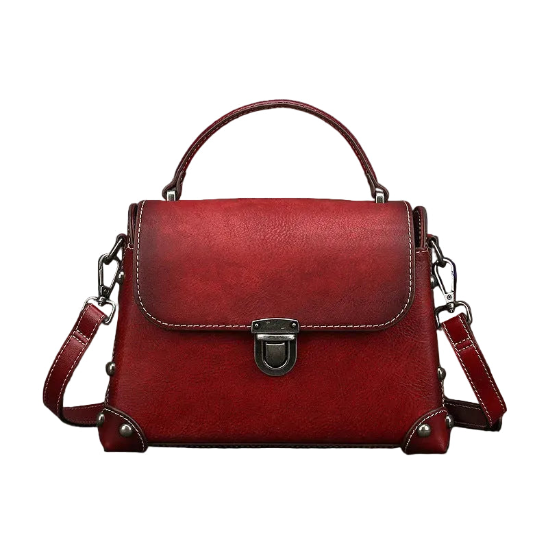 Red leather handbag with a silver clasp on a gray background