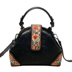 Black handbag with floral embroidery strap on a textured surface