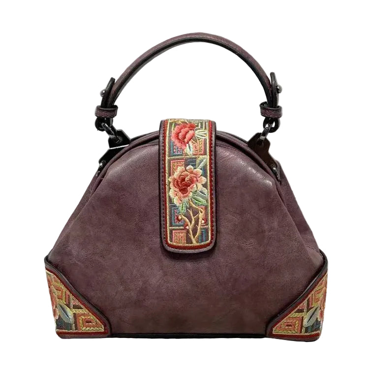 Brown handbag with floral embroidery on a gray surface
