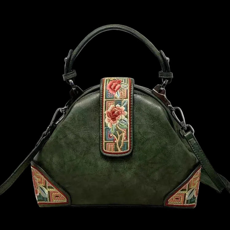 Green handbag with floral embroidery on a gray background