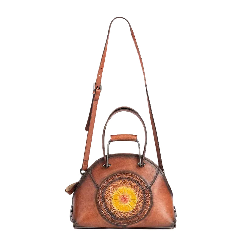 Brown leather handbag with a decorative circular design on a white background