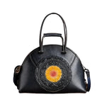Black handbag with a yellow flower design on a brown background