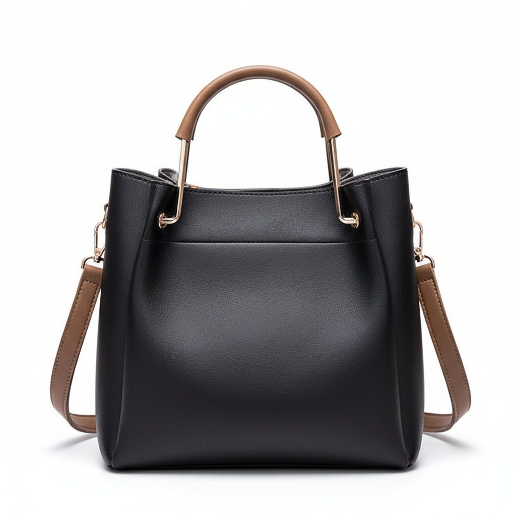 Black handbag with brown handles and strap on a wooden surface