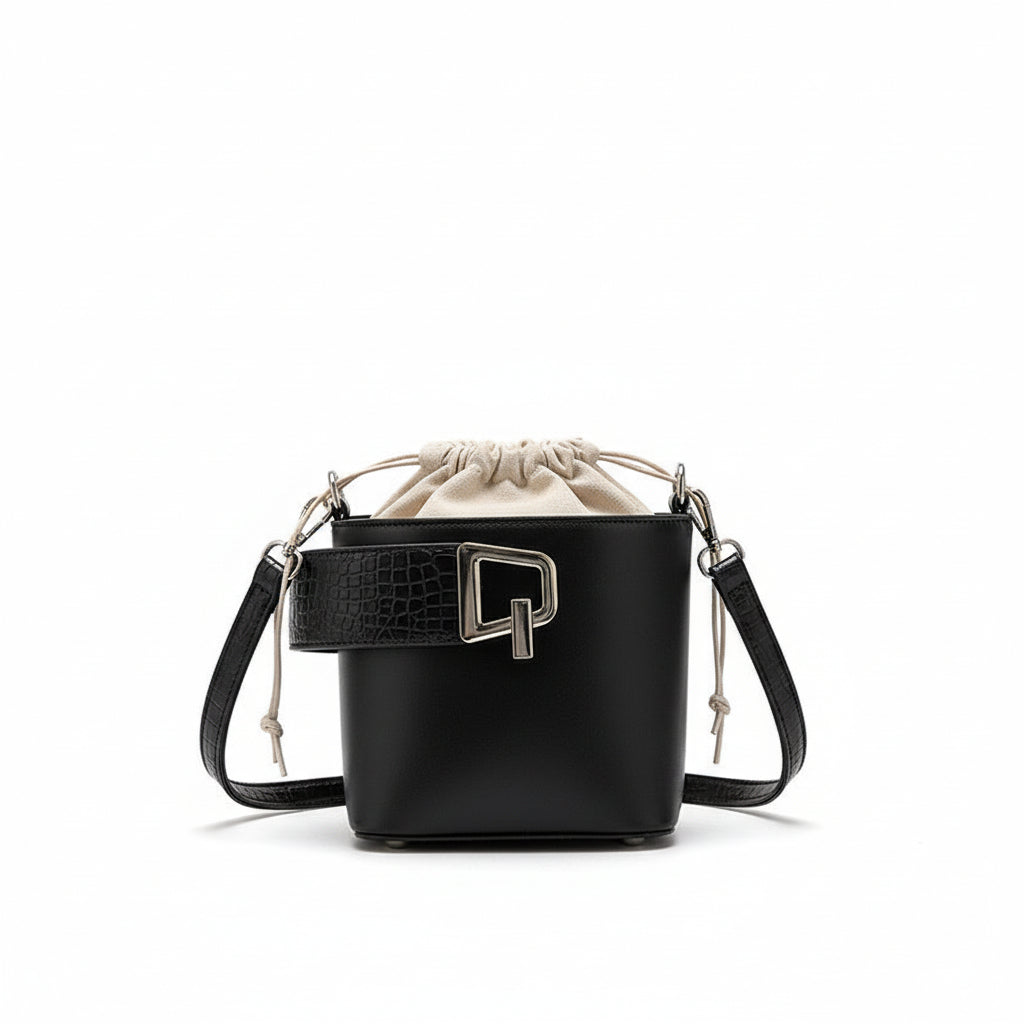 Black handbag with a bottle of perfume on a white fabric background