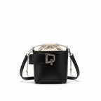 Black handbag with a bottle of perfume on a white fabric background