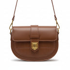 Brown leather handbag with gold accent held by a person wearing a beige sweater.