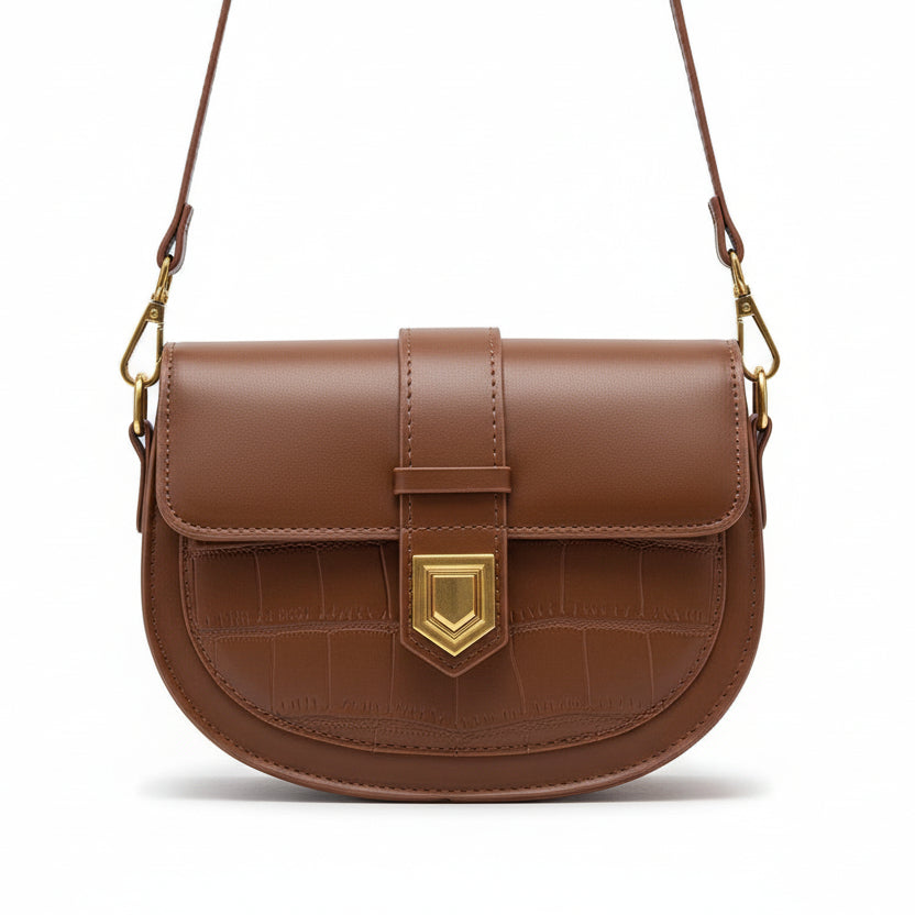 Brown leather handbag with gold accent held by a person wearing a beige sweater.