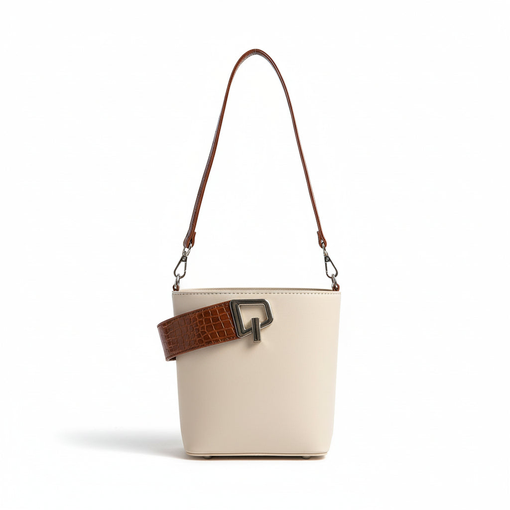 Beige handbag with brown strap and white blouse on a light fabric background