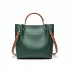 Green handbag with brown handle and strap on a wooden surface