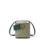 Green handbag with a strap on a white fabric surface
