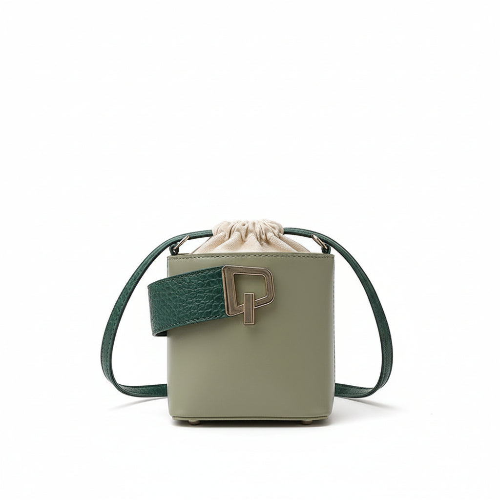 Green handbag with a strap on a white fabric surface