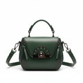 Green handbag on a wooden stand with 'ORIGINALS' branding on a wooden surface.
