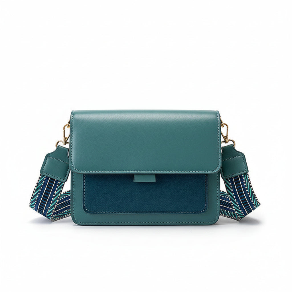 Green handbag with a striped strap held by a hand against a beige jacket background