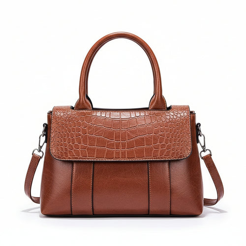 Brown handbag with crocodile texture on a white surface with a brown background