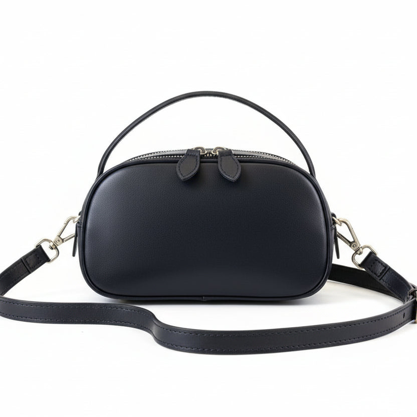 Black handbag on a light gray surface with a blurred background