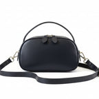 Black handbag on a light gray surface with a blurred background