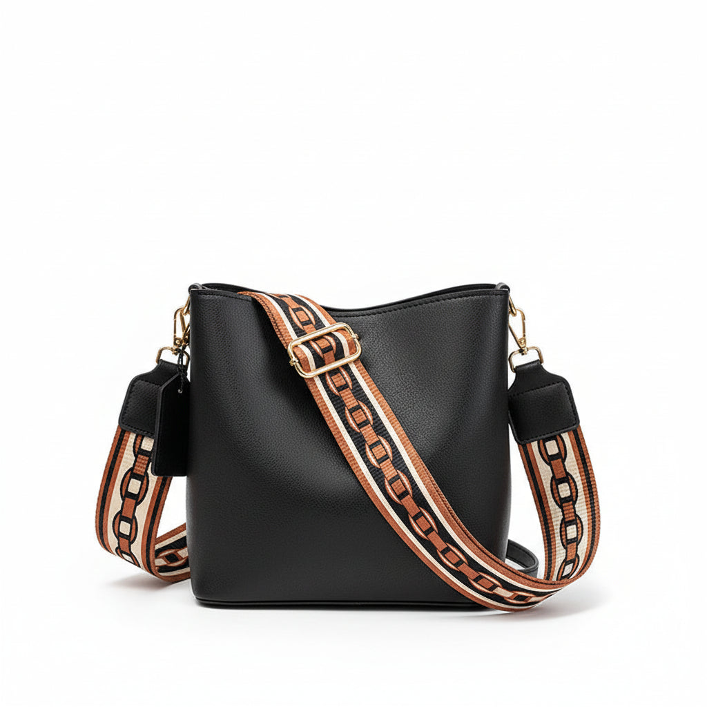 Black handbag with a patterned strap held by a person on a neutral background