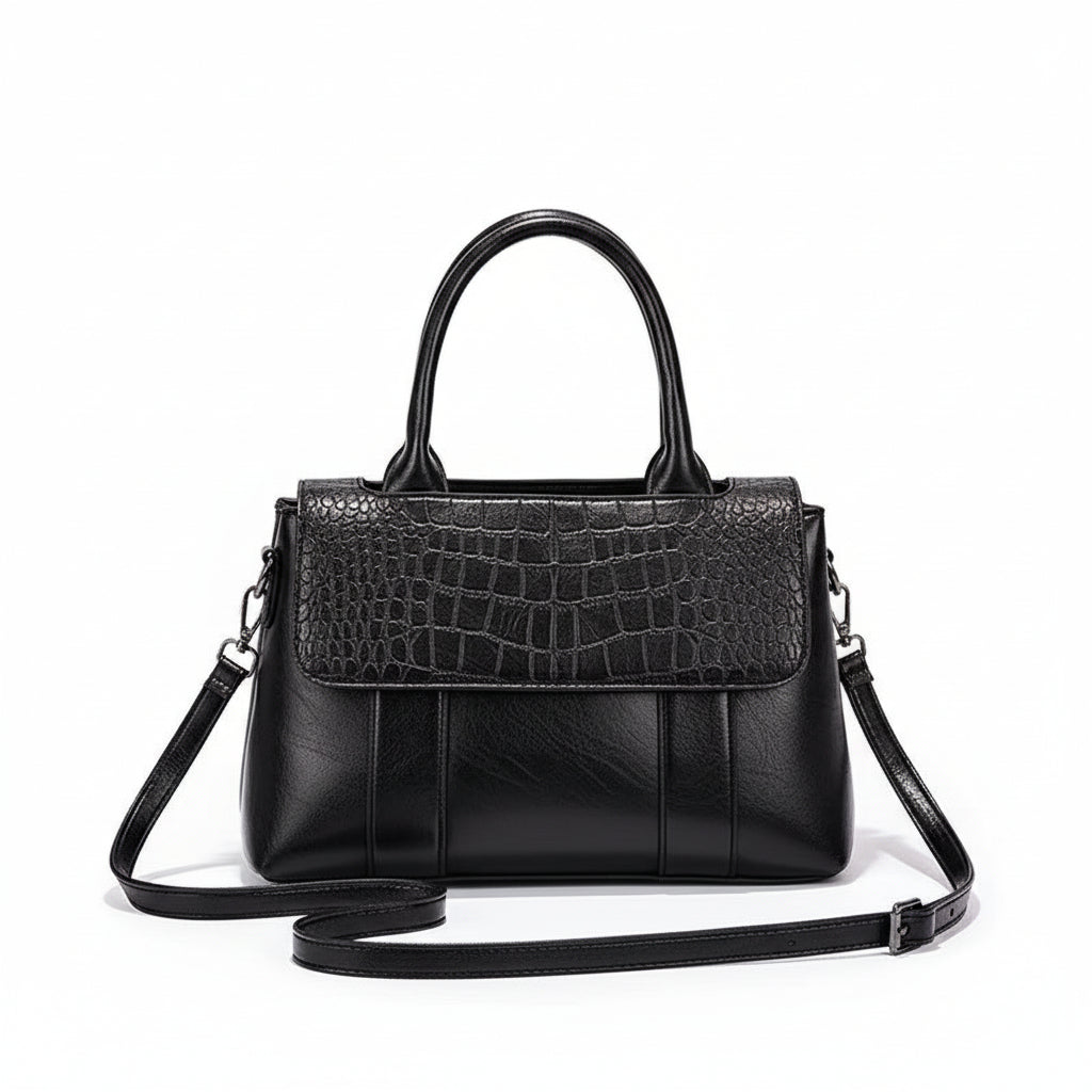 Black handbag with crocodile texture on a white surface with a brown background
