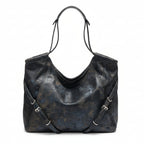 Black leather handbag on a hanger against a neutral wall.