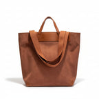 Brown tote bag on a white surface with a framed quote in the background.