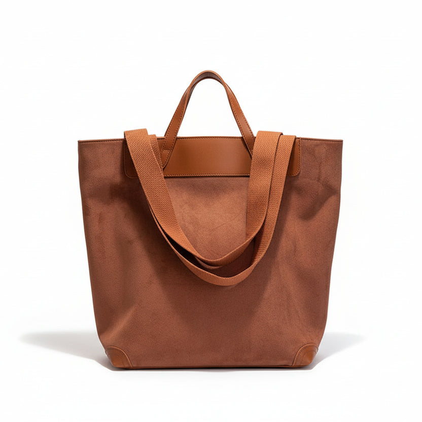 Brown tote bag on a white surface with a framed quote in the background.