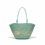 Green woven handbag on a hanger against a clothing rack background