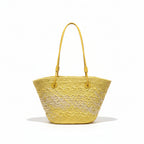 Yellow woven handbag hanging on a rack with clothing in the background
