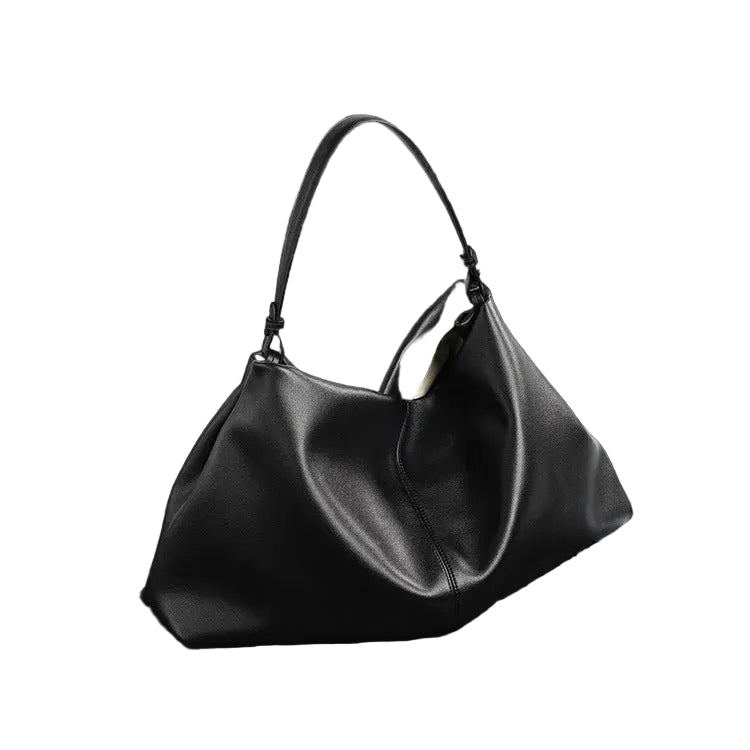 Black handbag on a dark surface with a white background