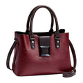 Red handbag with black accents on a light surface with a beige background