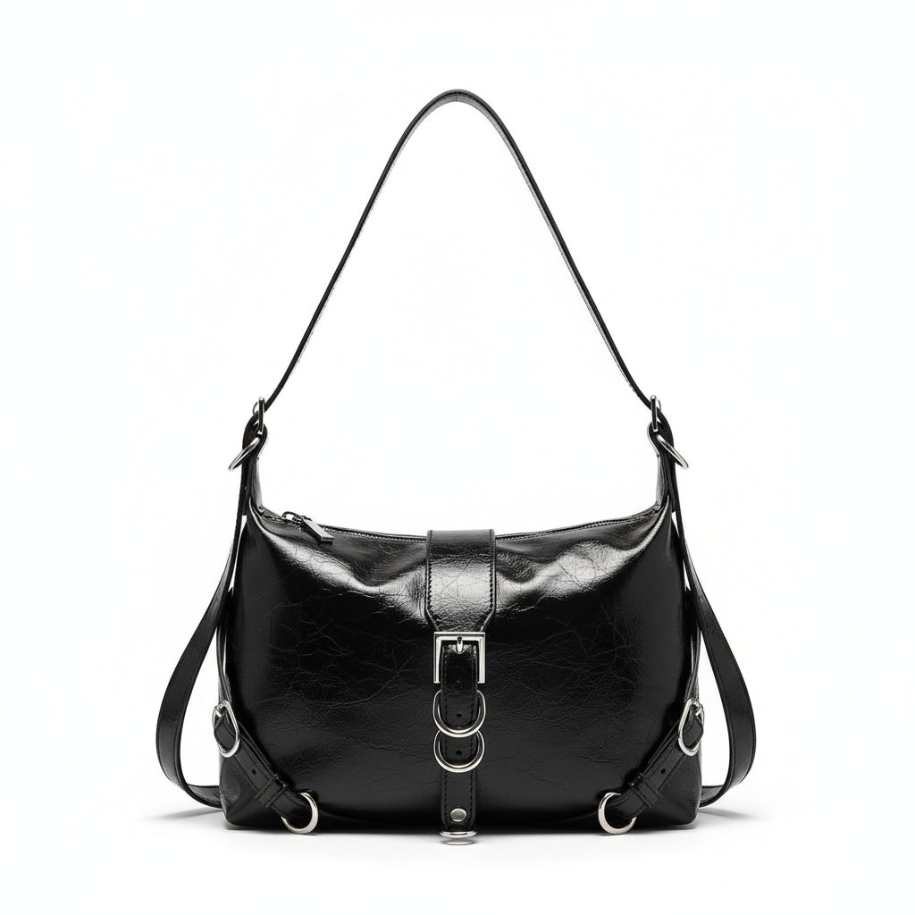 Black leather handbag held by a person against a neutral wall.