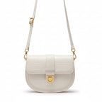 White handbag with gold accents worn by a person in a black outfit.
