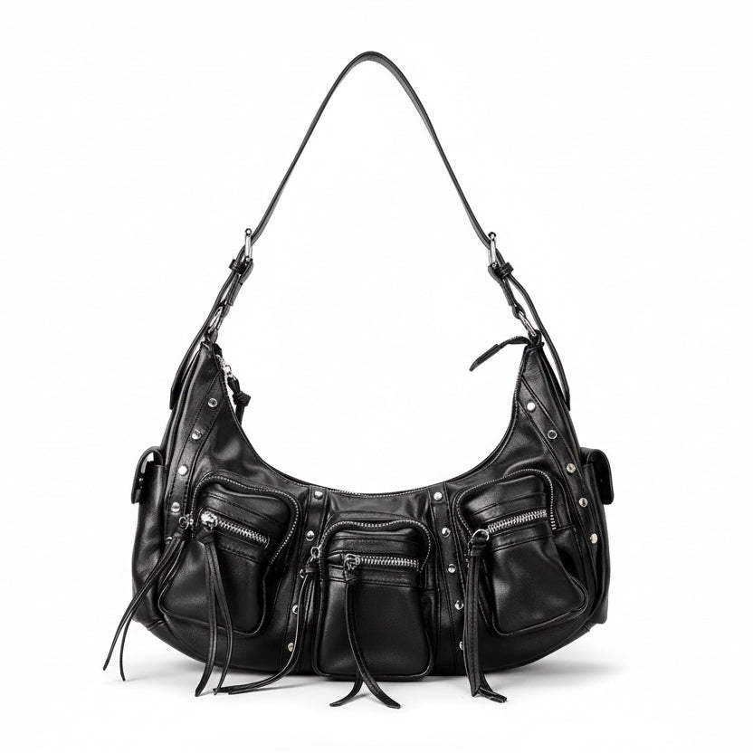 Black leather handbag with multiple zippers held by a hand on a light gray background